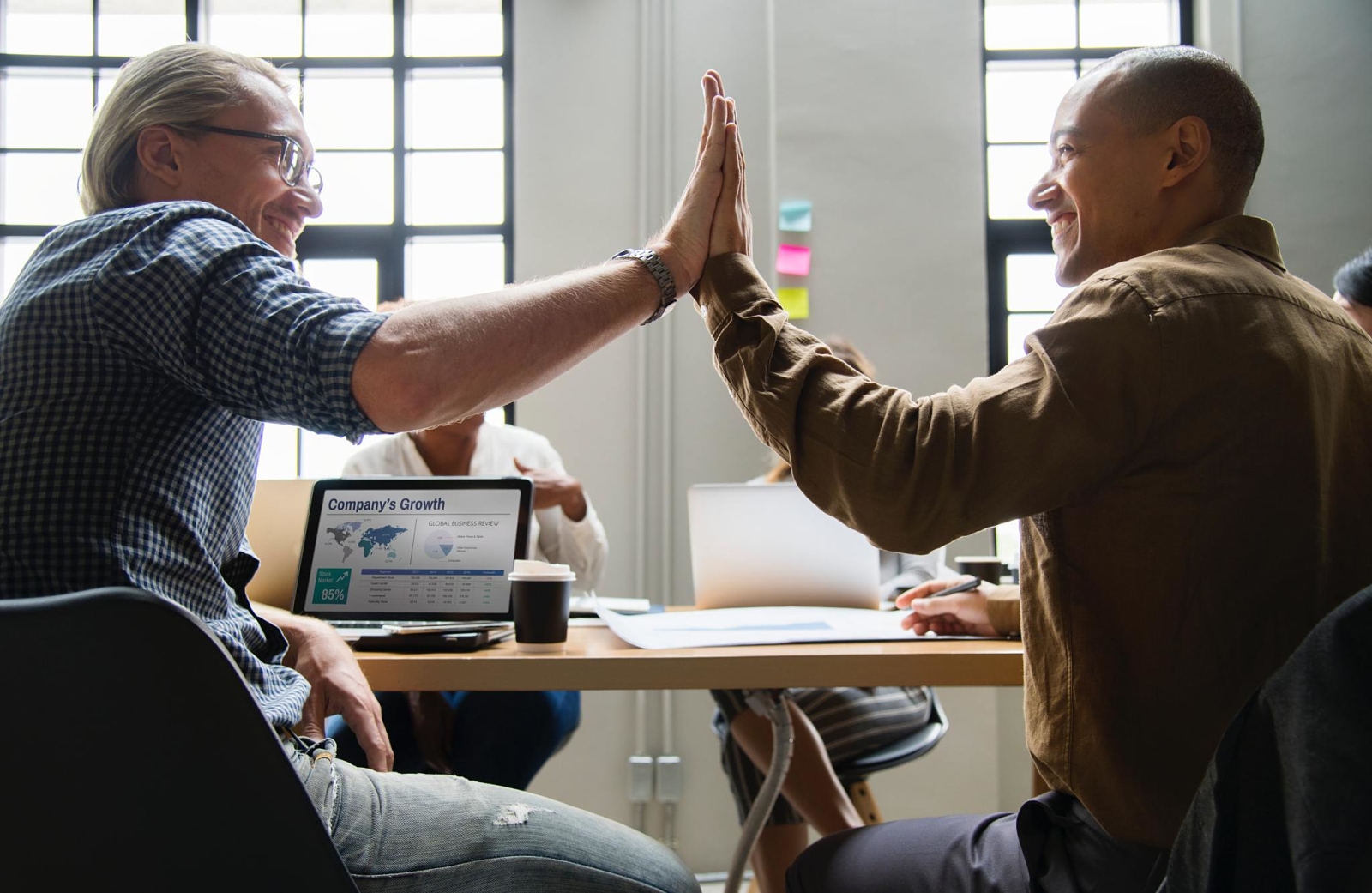 Two people sitting in a meeting, looking at each other in front of each other, crashing their hands. They look happy. Focused approach.