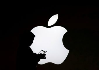 imagen de fondo negro con logo de Apple y se aprecia sombra de una persona manipulando un celular.