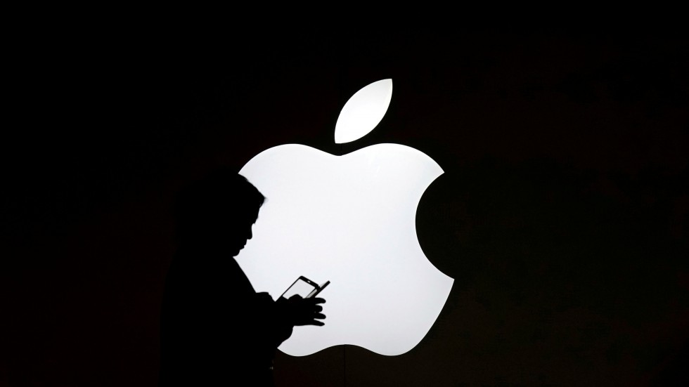 imagen de fondo negro con logo de Apple y se aprecia sombra de una persona manipulando un celular.